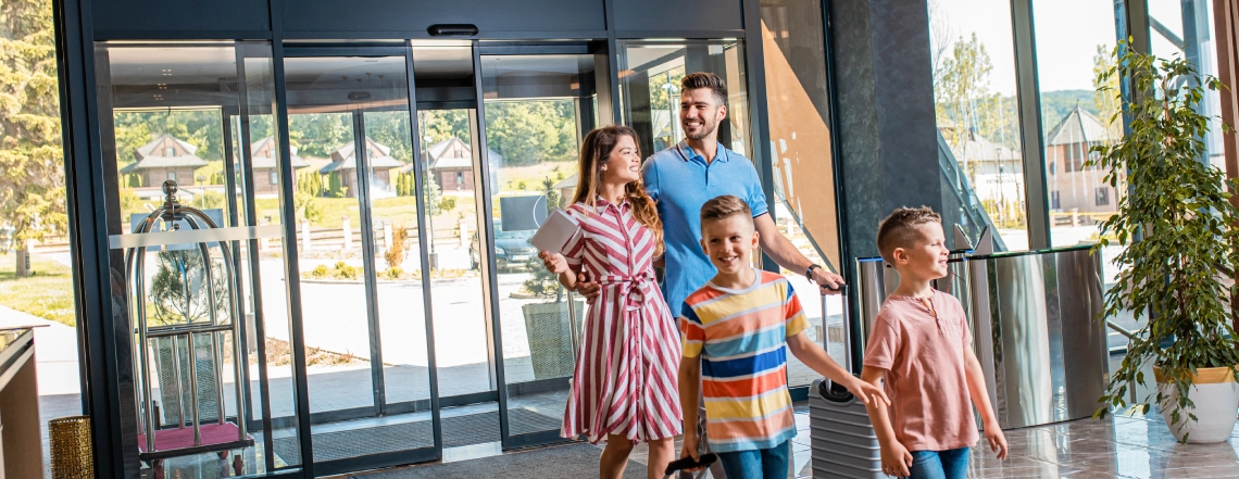 a-happy-british-family-with-two-kids-one-couple-of-husband-and-wife-are-coming-inside-of-hotel-from-automatic-sliding-doors