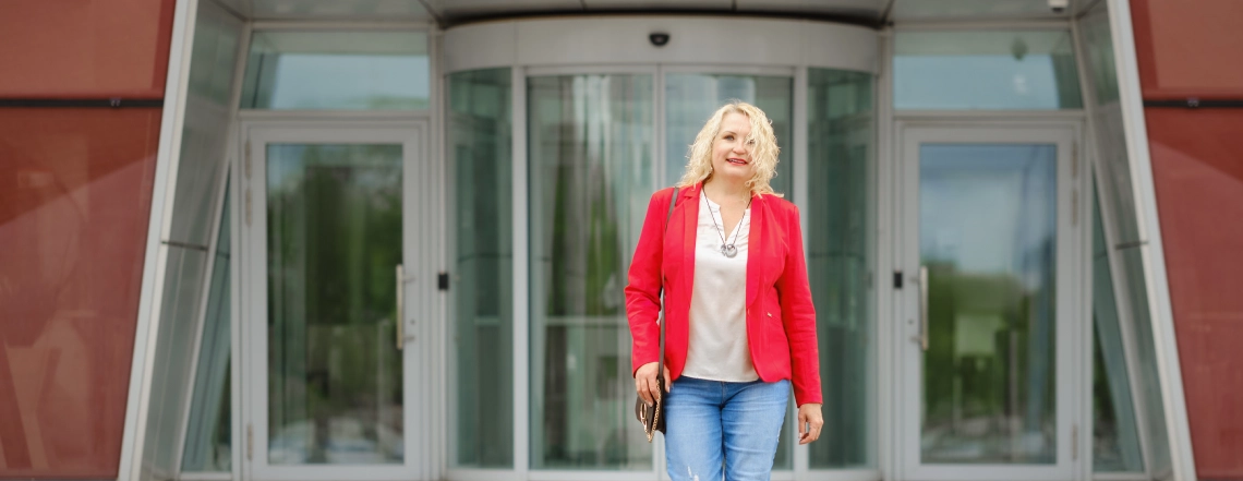 beautiful-british-blonde-lady-wearing-red-blazer-looking-professional-coming-out-from-automatic-curved-sliding-door